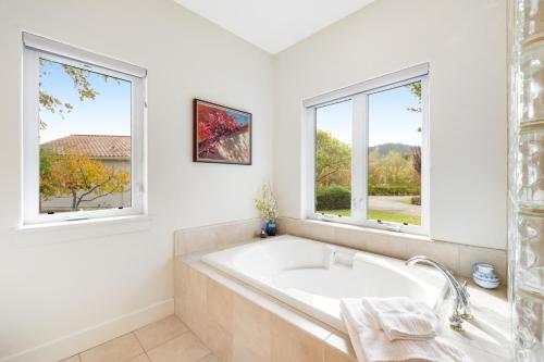- une salle de bains blanche avec baignoire et 2 fenêtres dans l'établissement Wine Country Vineyard Estate, à Kenwood