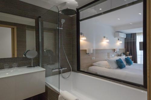 a bathroom with a bed and a shower and a tub at Hôtel La Roya in Saint-Florent