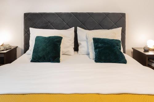 a white bed with two green pillows on it at Design 2BDR Apartment with Balcony- FREE PARKING in Zagreb