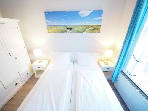 a white bedroom with a bed with two pillows at Haus Neptun App. 4 in Westerland (Sylt)