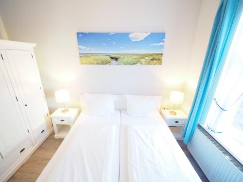 a white bedroom with a bed with two lamps and a painting at Haus Neptun App. 4 in Westerland (Sylt)