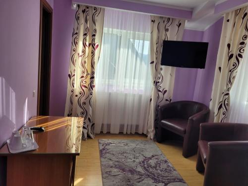 een woonkamer met paarse muren, een stoel en een raam bij Pension Tui in Sinaia