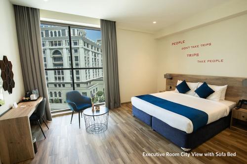 ein Hotelzimmer mit einem Bett und einem großen Fenster in der Unterkunft Grand Kingsgate Jaddaf Waterfront Hotel by Millennium in Dubai