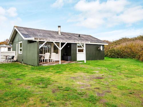 a green house with a table and chairs in a yard at 6 person holiday home in Hvide Sande in Nørre Lyngvig