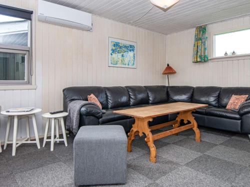 a living room with a black leather couch and a table at 6 person holiday home in Hvide Sande in Nørre Lyngvig