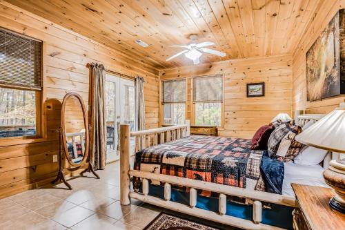 a log cabin bedroom with a bed and a ceiling fan at Emerald Forest in Ellijay