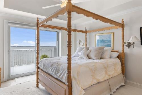 een slaapkamer met een hemelbed en een groot raam bij Nautical Club #702 in Atlantic Beach