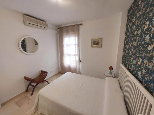 een witte slaapkamer met een bed en een stoel bij Carlos Cañal in Sevilla