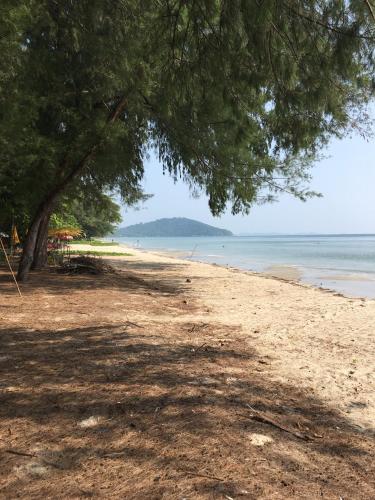 a sandy beach with a tree and the ocean at Vip condo chain by Linda in Ban Phe