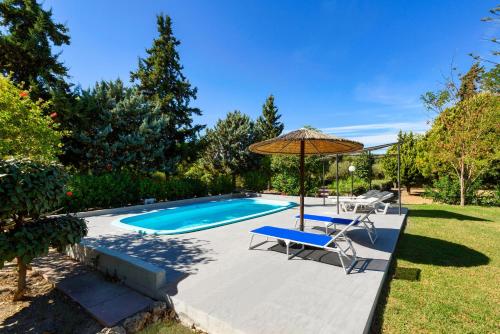 a swimming pool with an umbrella and two chairs and a table and an umbrella at Villa Kleio in Ialyssos