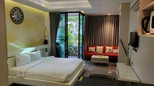 a bedroom with a bed and a couch and a clock at Naiharn Relife by Nataly in Nai Harn Beach