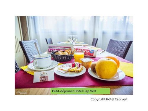 - une table avec petit-déjeuner composé de fruits et de jus d'orange dans l'établissement Hôtel CAP VERT en Aveyron, à Saint-Affrique