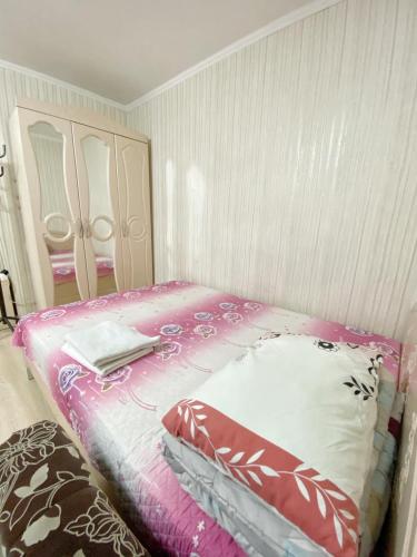 um quarto com uma cama com um edredão rosa e branco em Ahmetova 4 30 em Almaty