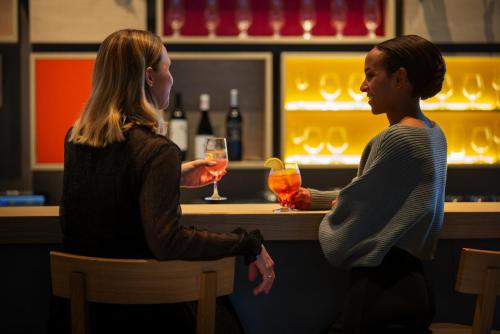 two women sitting at a bar with drinks at IntercityHotel Zürich Airport in Rümlang