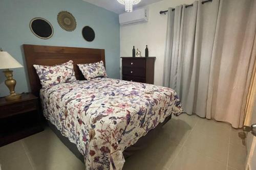 um quarto com uma cama com uma colcha floral e uma mesa em Apartamento Moderno y Confortable con piscina em Santiago de los Caballeros