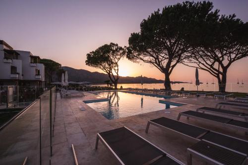 une piscine avec vue sur le coucher du soleil en arrière-plan dans l'établissement Hôtel La Roya, à Saint-Florent