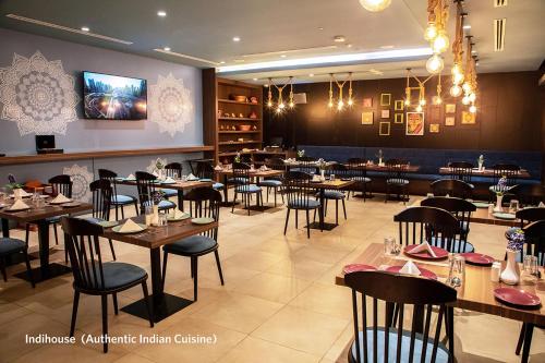 une salle à manger avec des tables et des chaises dans un restaurant dans l'établissement Kingsgate Canal Hotel by Millennium, à Dubaï
