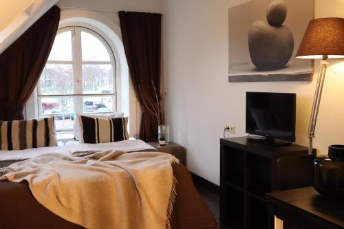um quarto com uma cama, uma televisão e uma janela em Bar-Bistro-Hotel DOK em Steenbergen