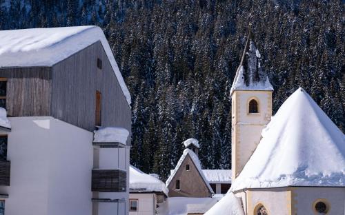 a church with a snow covered roof and a building at Zum Hirschen Boutique Hotel Val di Non in Unsere Liebe Frau im Walde