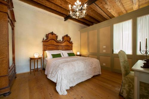 a bedroom with a large bed and a chandelier at Villa Premoli - Agriturismo di charme in Cavaso del Tomba