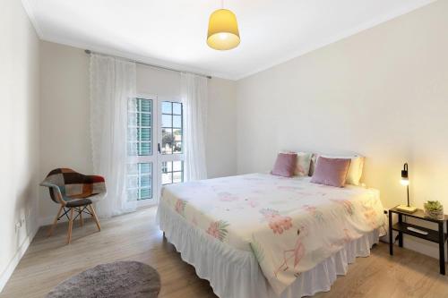 a white bedroom with a bed and a window at Villa As Cumadres in Azeitao