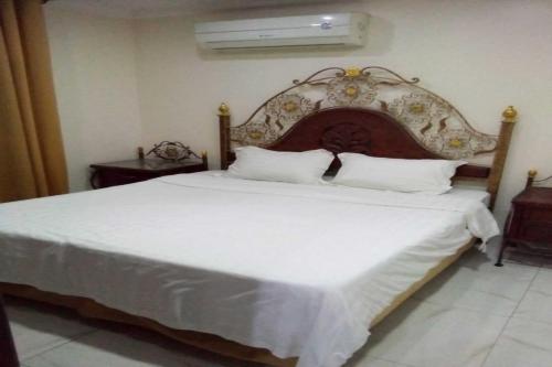 a bedroom with a large white bed with a wooden headboard at OYO 639 Home Furnished Apartments - 2BHK in Al Khobar