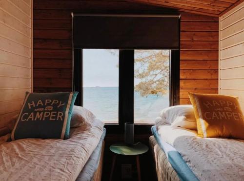 two beds in a room with a view of the ocean at Beach Cottage in Hanko