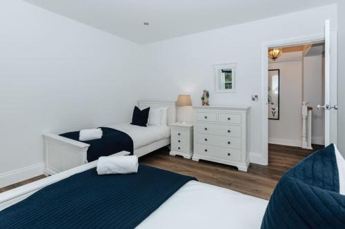 a white bedroom with two beds and a dresser at Woodvale Retreat in Harpsden