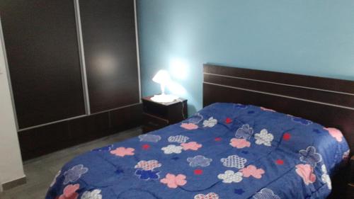 Un dormitorio con un edredón azul con flores. en Residencia Schneider en Junín
