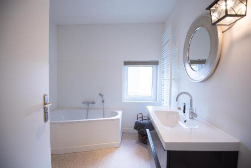 een badkamer met een bad, een wastafel en een spiegel bij Jeanneke Bosch in Schin op Geul