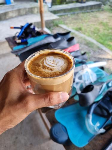 a person holding up a cup of coffee at RUSTIQUE RUE Mabini - Hostel in Batangas City