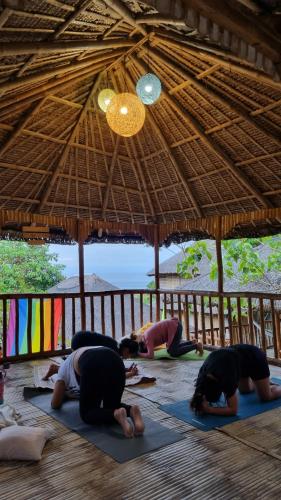 a group of people doing yoga under a straw hut at RUSTIQUE RUE Mabini - Hostel in Batangas City