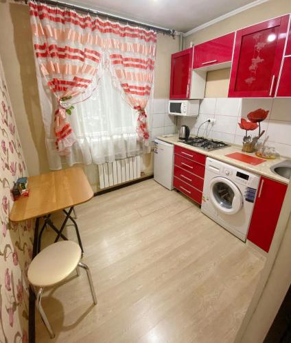 a small kitchen with red cabinets and a washing machine at Ahmetova 4 30 in Almaty