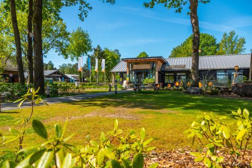 a building in a park with trees and grass at Europarcs De Wije Werelt in Otterlo