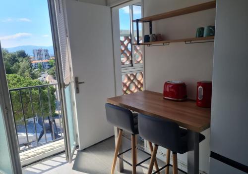 a small kitchen with a table and chairs and a balcony at Escapade Montesquieu in Perpignan