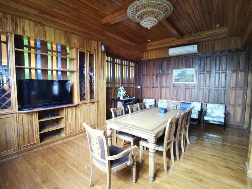 a dining room with a table and chairs and a tv at Thai traditional wooden house in Ban Nong Bu