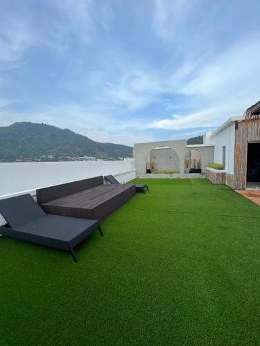 Aloha Residence في شاطئ كاتا: ساحة خضراء مع أريكة على سقف منزل
