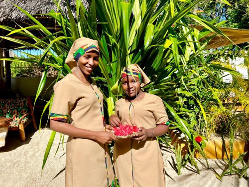 two women standing next to each other holding a bowl of fruit at Chikachika Beach B&B in Nungwi