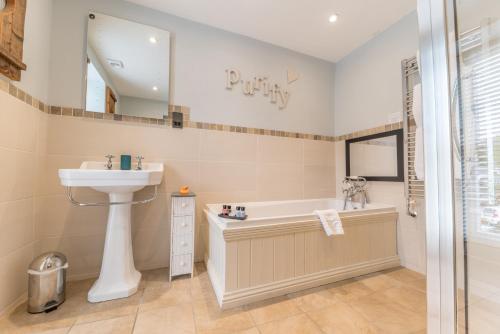 a bathroom with a sink and a bath tub and a mirror at Heidi's Grasmere Lodge in Grasmere