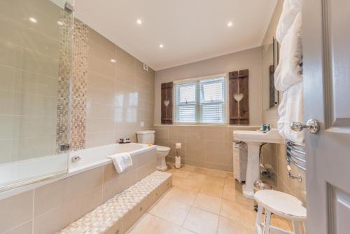 a bathroom with a tub and a toilet and a sink at Heidi's Grasmere Lodge in Grasmere