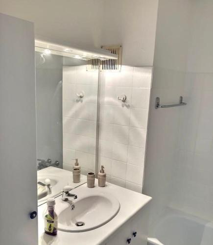 a white bathroom with a sink and a mirror at Studio met frontaal zeezicht in Ostend