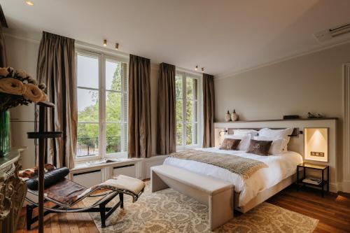 a bedroom with a bed and a chair and windows at Manoir François du Tilleul - Reims - Fismes in Fismes