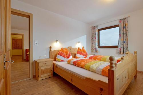 a bedroom with a wooden bed with orange pillows at Embacher Marianne - Rotharlhof in Hopfgarten im Brixental