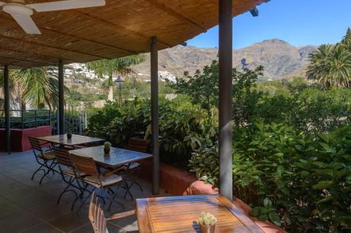 two tables and chairs on a patio with mountains in the background at Hotel Rural Las Longueras in Agaete