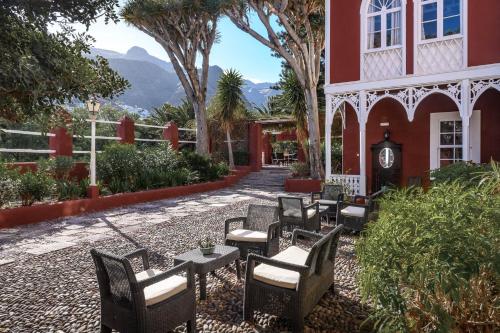 a patio with tables and chairs in front of a red building at Hotel Rural Las Longueras in Agaete