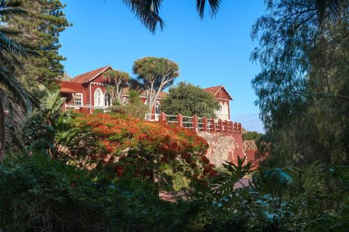 a house on a hill with a fence and trees at Hotel Rural Las Longueras in Agaete
