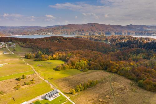 an aerial view of a field with trees and a lake at Bieszczadzkie Siedlisko in Polańczyk