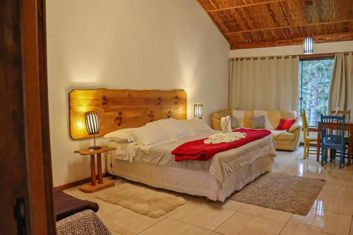 una camera con un grande letto e un divano di Pousada Chalés do Lago a Visconde De Maua