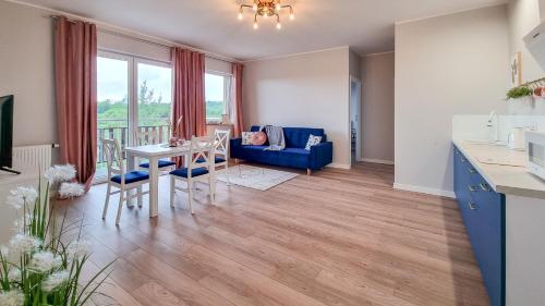 a kitchen and living room with a table and a blue couch at Apartamenty Sun & Snow Baltic Nova in Władysławowo