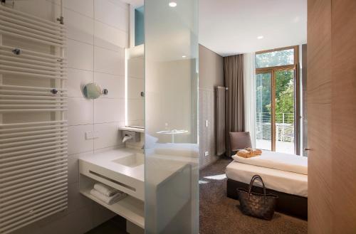a bathroom with a sink and a bed and a mirror at Parkhotel Jordanbad in Biberach an der Riß